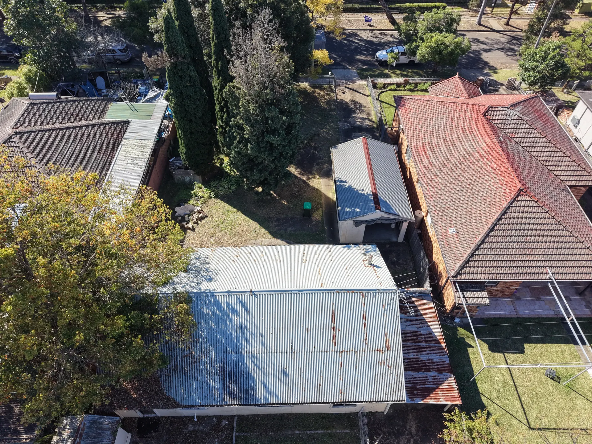 Close aerial view of the building's corrugated-iron roof, with rust spread across several sheets and a lower skillion section at one end.